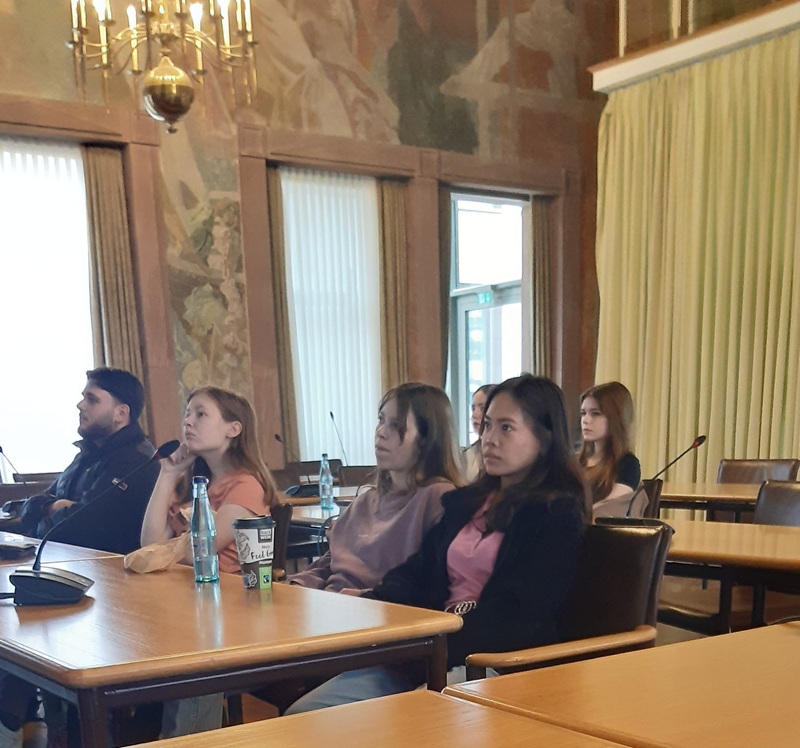 Beeindruckende Zeitreise – 80 Jahre Kriegsende Die Schülerinnen und Schüler der Euro Akademie Aschaffenburg sitzen in einem großen Saal des Aschaffenburger Rathauses, an der Decke hängt ein opulenter Lüster.