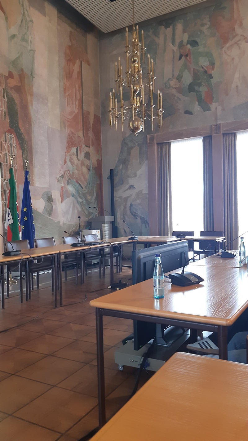 Beeindruckende Zeitreise – 80 Jahre Kriegsende Blick in einen großen Saal des Aschaffenburger Rathauses, mit opulentem Lüster an der hohen Decke, Europafahne im Hintergrund.