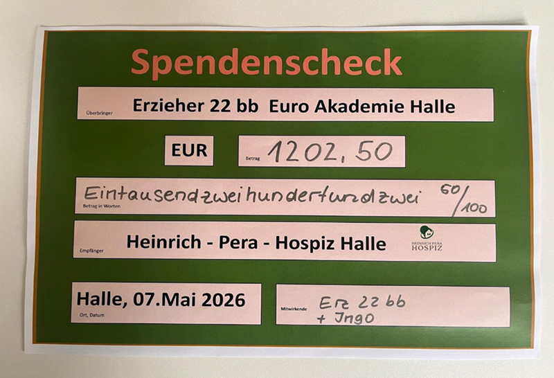 Ein großformatiger Spendenscheck mit grünem Hintergrund und gelbem Schriftzug. In der Mitte steht der Betrag '1202,50 EUR', ausgeschrieben als 'Eintausendzweihundertzwei 60/100'. Der Scheck ist adressiert an das 'Heinrich-Pera-Hospiz Halle'. Oben links steht der Aussteller 'Erzieher 22 bb Euro Akademie Halle'. Unten rechts sind Unterschriftenfelder ausgefüllt. Das Ausstellungsdatum ist '07. Mai 2026'. Mehrere Logos und Felder sind klar voneinander abgegrenzt.