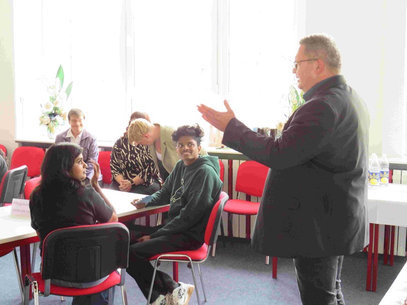 Die neuen Auszubildenden sitzen im Klassenzimmer und hören einem Mitarbeitenden zu. 