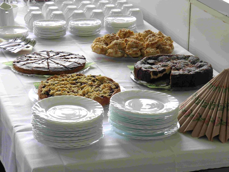 Kuchenbuffet mit verschiedenen selbst gebackenen Kuchen, Tellern, Tassen und Besteck.