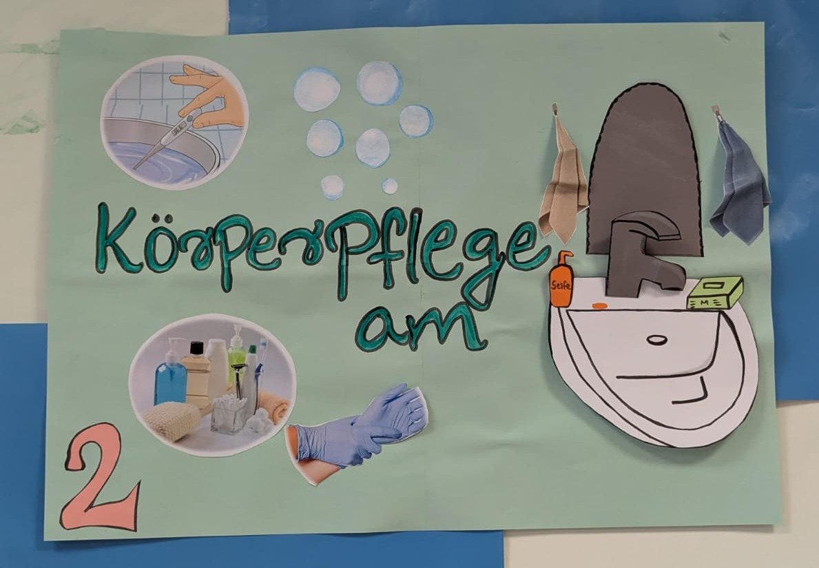 Auf einem Plakat steht geschrieben: "Körperpflege am", daneben ist ein Waschbecken aufgezeichnet. Außerdem sind ähnlich einer Collage noch weiter Bilder aufgeklebt: ein Thermometer, das ins Wasser gehalten wird, Pflegeprodukte, Hände in Plastikhandschuhen. In der linken unteren Ecke befindet sich die Ziffer 2.