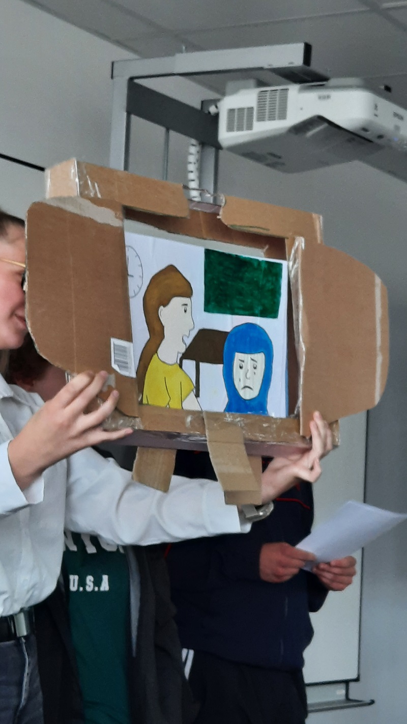 Sprache – ein Schlüssel zur Welt Selbst gestaltetes Kamishibai, das eine traurige Frau mit Kopftuch zeigt und eine andere, die freundlich zu ihr spricht.