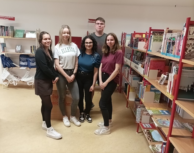 Die angehenden Erzieherinnen und Erzieher der Euro Akademie Magdeburg posieren für ein Gruppenfoto in der Bibliothek.