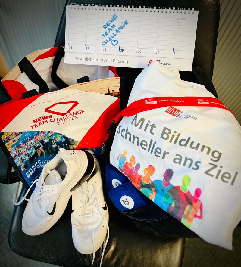 Unsere Teams laufen los – REWE Team Challenge 2025 In einem aufgeklappten Tischkalender der ESO Education Group ist für den 28. Mai 2025 der REWE Team Challenge Lauf 2025 eingetragen, der auf einer Mehrwegtasche mit REWE Team Challenge Aufdruck sowie einem Jute Beutel der ESO Education Group mit Aufschrift "Mit Bildung schneller ans Ziel".