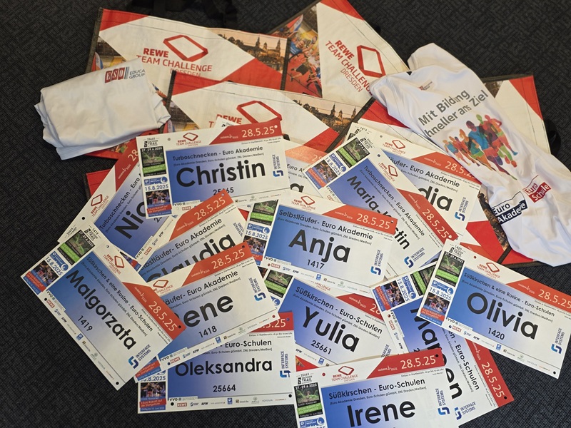 Unsere Teams laufen los – REWE Team Challenge 2025 Startnummern für die REWE Team Challenge mit Namen der Mitarbeitenden der Euro Akademien und Euro-Schulen liegen auf einem Haufen, dazwischen bedruckte Euro Akademie und Euro-Schulen Teilnehmer-T-Shirts.