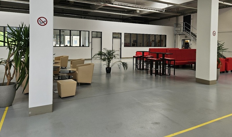 Rückblick auf unseren Tag der offenen Tür Blick in die Eingangsbereich der Euro Akademie Nürnberg, mit modernen Sitzgelegenheiten und Garnituren in beige und rot, gläsernen Tischen und schönen, groß gewachsenen Pflanzen in sattem Grün.