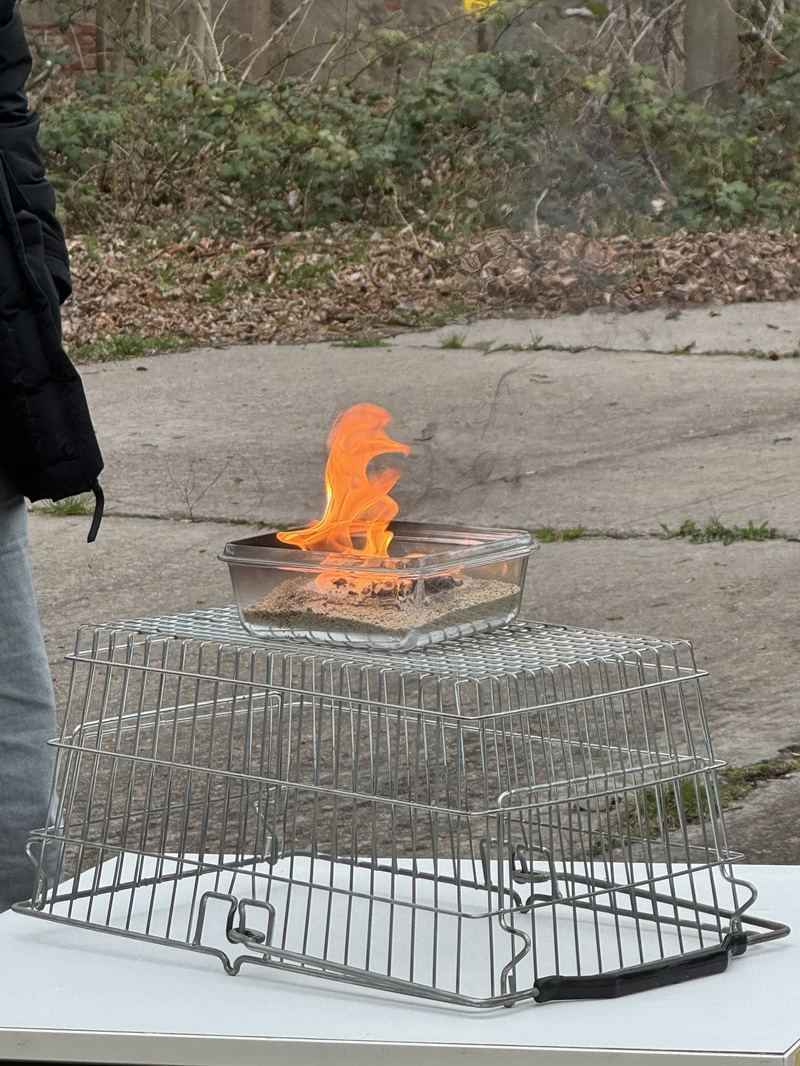 Heiße Pharao-Schlange Das Gemisch in der Glasschale brennt kontrolliert und steht dabei auf einem Drahtkorb auf dem Tisch.