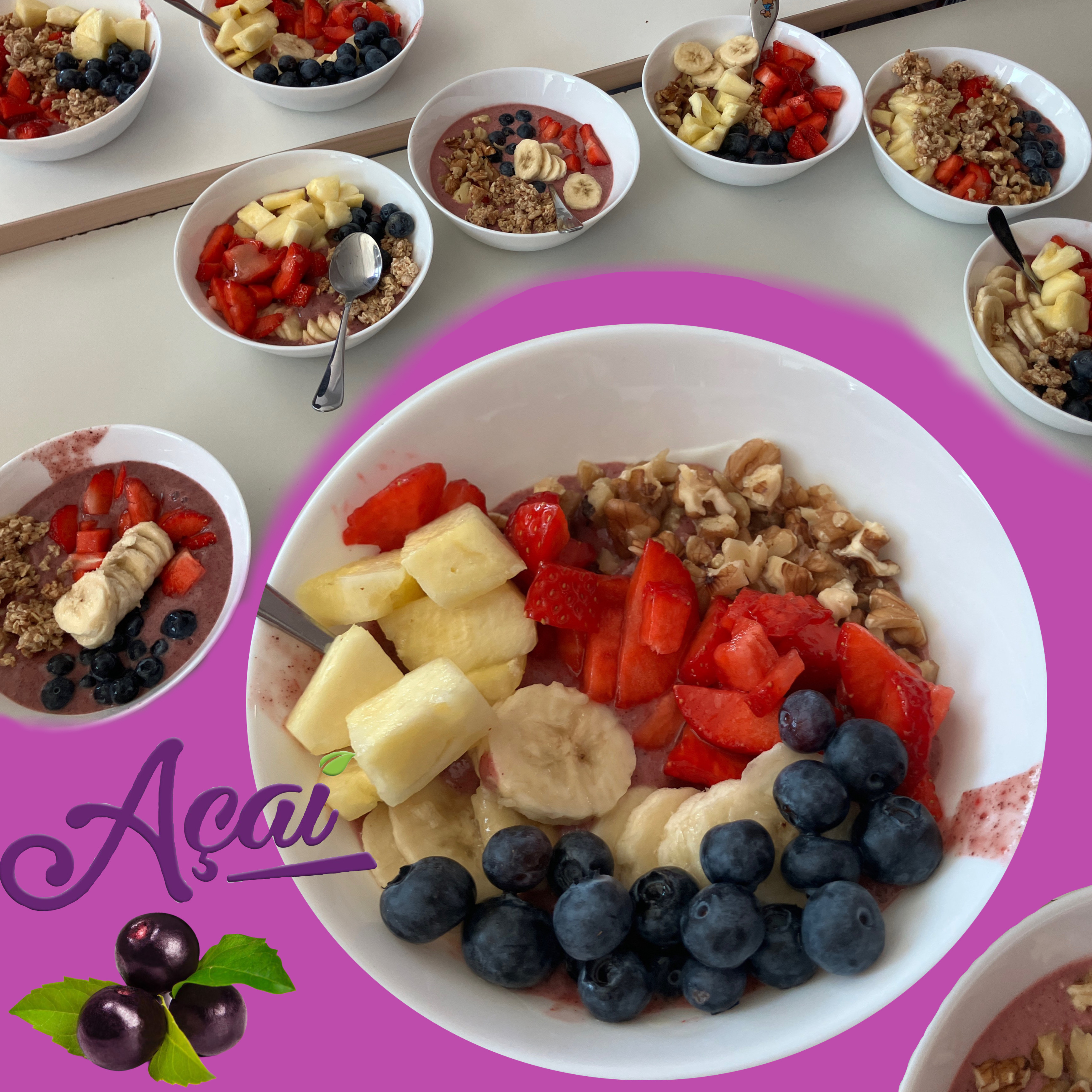 Mehrere Schalen mit Açaí-Creme, Müsli, Nüssen und frischem Obst wie Erdbeeren, Blaubeeren, Banane und Ananas; im Vordergrund ist eine große Schale dekorativ hervorgehoben.