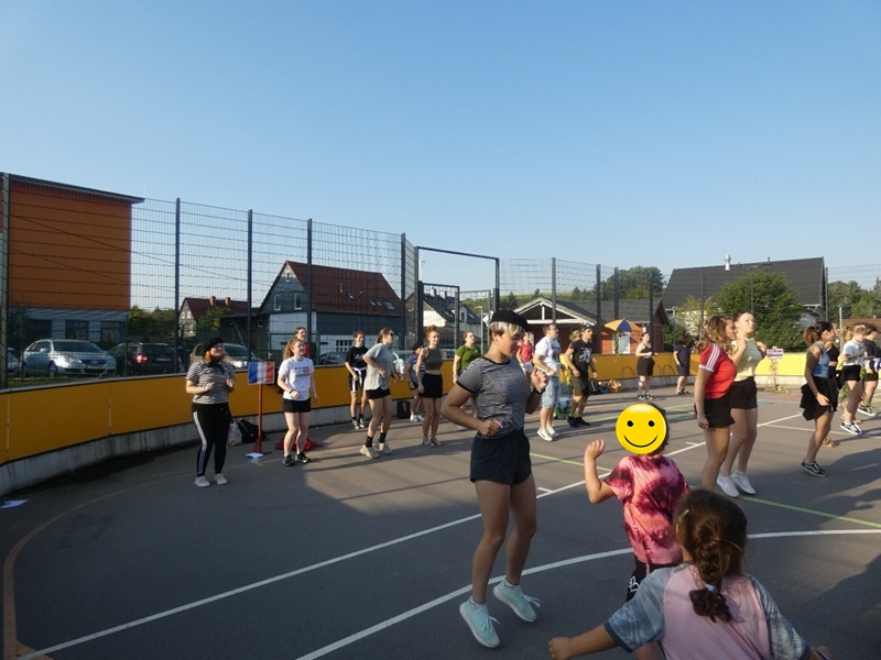 Kinder und die Auszubildenden draußen auf dem Sportplatz, hüpfen und bewegen sind.