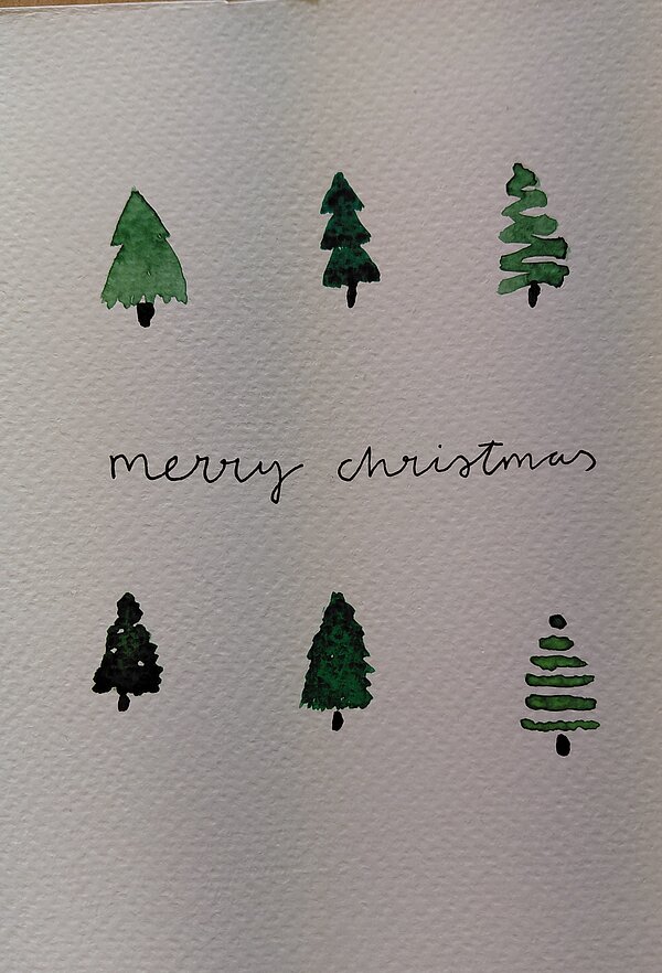 Handgemalte Grußkarte mit sechs kleinen Tannenbäumen in unterschiedlichen Grüntönen und der Aufschrift „merry christmas“ in Schreibschrift in der Mitte.