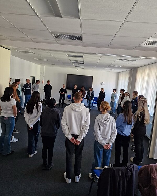 Theaterbesuch und Workshop Alle Auszubildenden stehen im Kreis im großen Raum, in dem der Theaterworkshop stattfindet.
