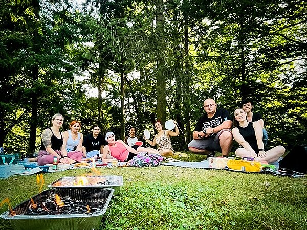 Willkommen zurück! Die Auszubildenden im zweiten Ausbildungsjahr sitzen auf Decken im Stadtpark und grillen und picknicken.