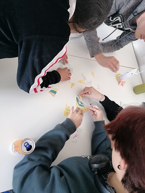 Teamwork Schülerinnen und Schüler der Euro Akademie Zwickau sind über einen Tisch gebeugt und arbeiten an einer Aufgabe.