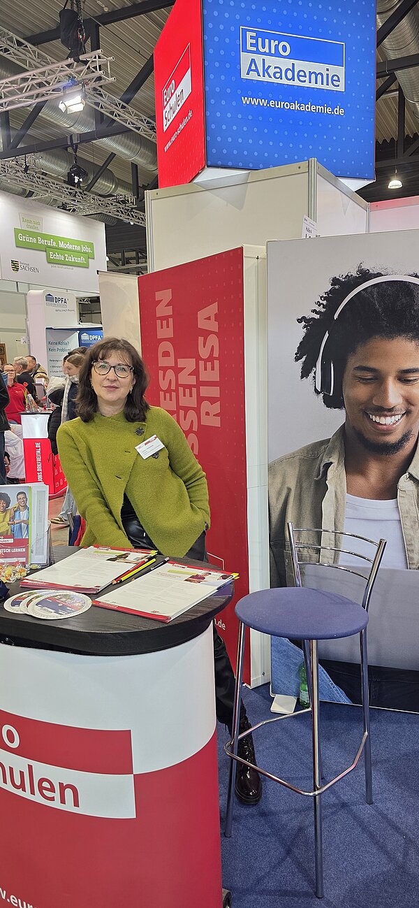 Eine Frau in grünem Blazer am Messestand der Euro-Schulen und Euro Akademie
