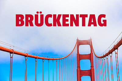 In großen roten Lettern steht BRÜCKENTAG über einer roten Hängebrücke, die stark an die Golden Gate Bridge erinnert, der Hintergrund ist himmelblau.