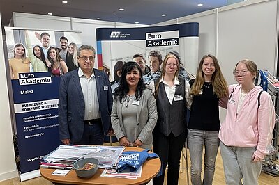 Gruppenfoto am Euro Akademie Messestand mit fünf Teammitgliedern