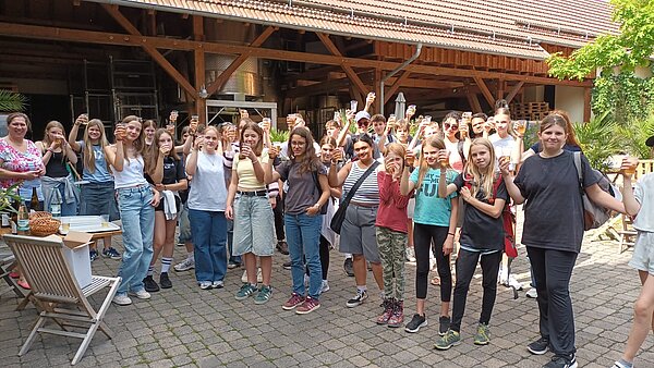 Sprachferien der Euro Akademie Jena und Erfurt: eine 20-jährige Erfolgsgeschichte Eine Gruppe von Kindern und Jugendlichen stehen in einem Halbkreis in einem Innenhof bei sonnigem Wetter.