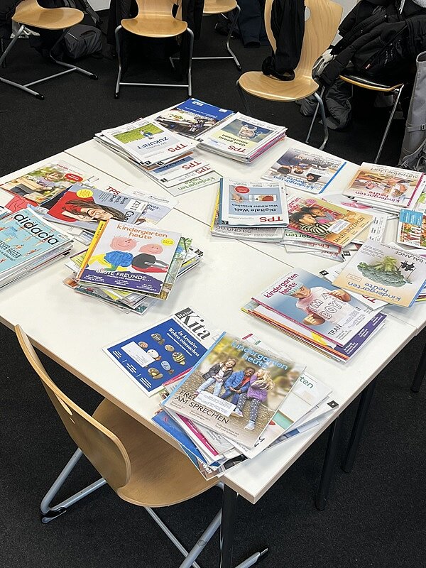 Facharbeitstag in Würzburg Auf einem Tisch liegen viele Broschüren, Zeitschruften und Literatur zum Thema Kindergarten und Pädagogik.