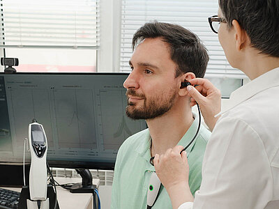 Das Bild zeigt eine medizinische Fachkraft, die das Ohr eines Patienten untersucht. Eine gängige Gesundheitsuntersuchung.