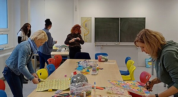 Bundesvorlesetag 2024 Erzieherinnen basteln mit allerlei Utensilien an einem langen Tisch.