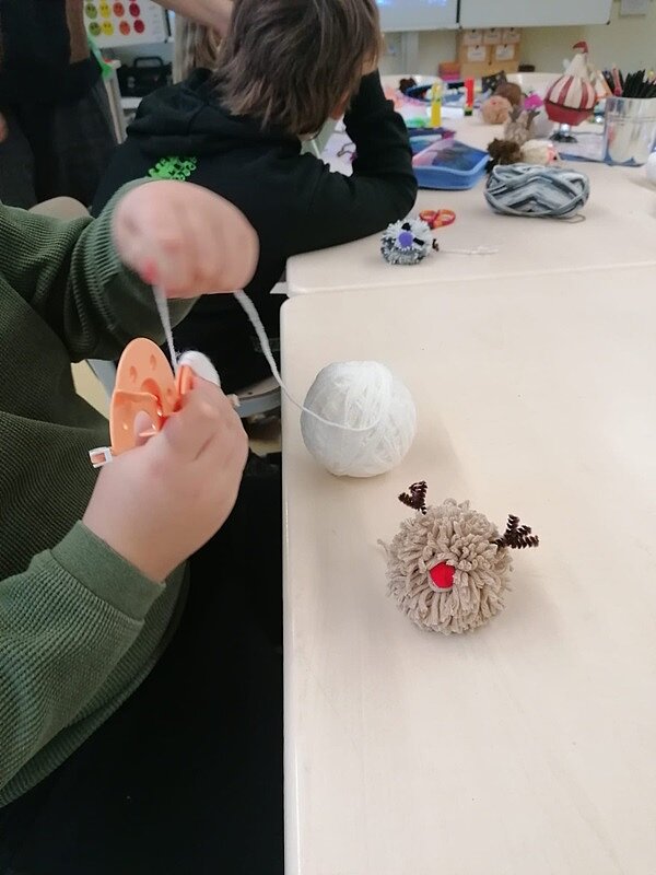 Engagiert und kreativ Kinderhände, die weihnachtliche Objekte aus Wolle basteln.