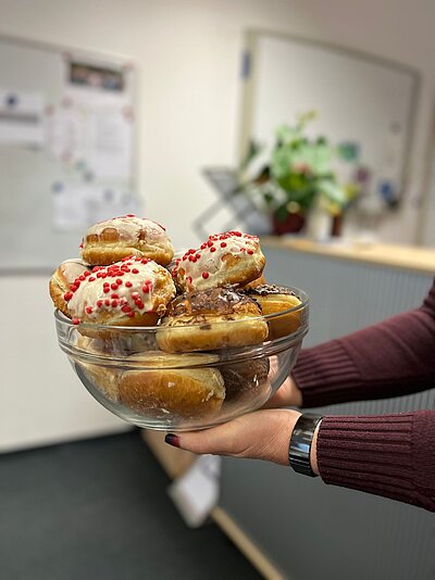 Eine Frau hält ein Glasgefäß mit Krapfen-Gebäck in Bild.