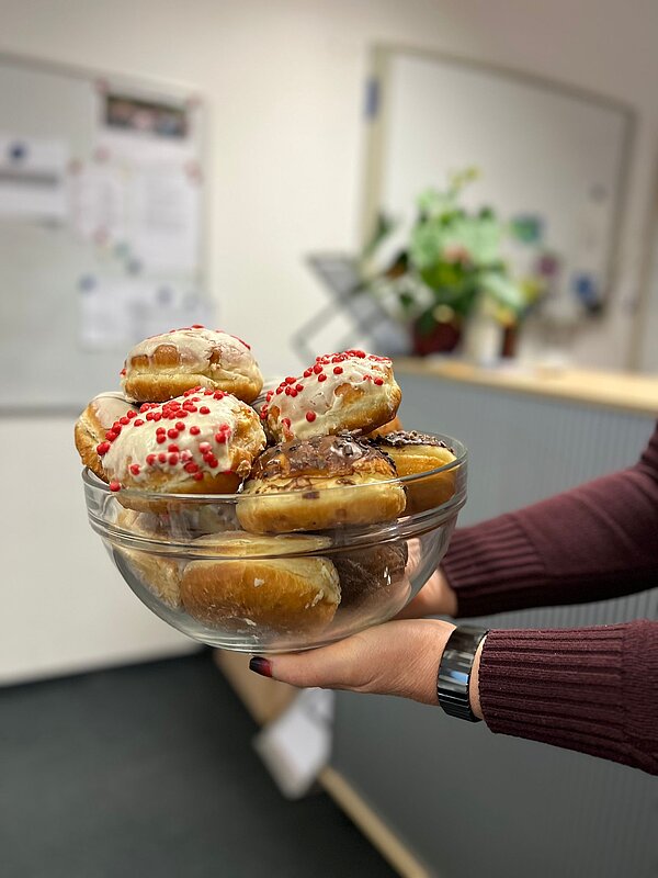 Kulinarischer Karneval-Auftakt Eine Frau hält ein Glasgefäß mit Krapfen-Gebäck in Bild.