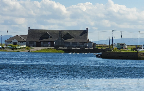 Ein Haus mit Strohdach der Stadt Galway an der irländischen Küste. Im Vordergrund ist das Meer zu sehen.