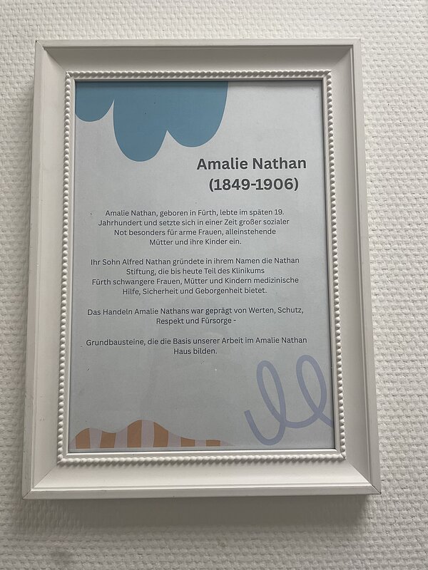 In einem weißen Bilderrahmen hängt ein Text über Amalie Nathan.