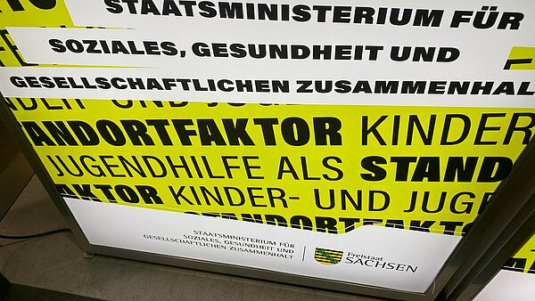 Deutscher Kinder- und Jugendhilfetag 2025: „Heute laut, morgen stark“ Foto einer gelb-schwarzen Leuchtreklame des sächsischen Staatsministeriums für Soziales, Gesundheit und gesellschaftlichen Zusammenhalt. Die Slogans sind nur teilweise zu lesen, einer könnte heißen: JUGENDHILFE ALS STANDORTFAKTOR