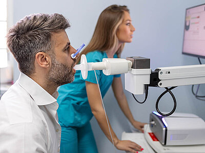 Auf dem Bild ist eine Lungenuntersuchung zwischen einem Arzt und einem Patienten zu sehen.