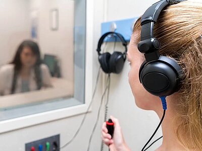 Person mit Kopfhörern an Audiogerät.