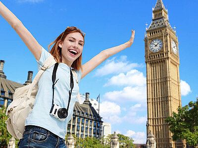 Eine Person mit erhobenen Armen vor dem Big Ben. Der Himmel ist klar, und es gibt einige Wolken.