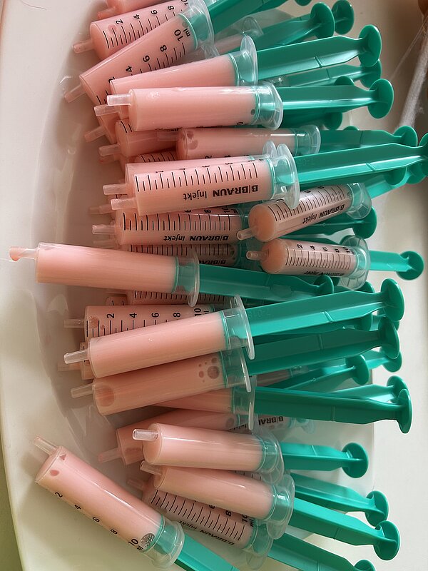 Tablett voller Einwegspritzen, gefüllt mit rosa Getränk, als Halloween-Shots/Deko.