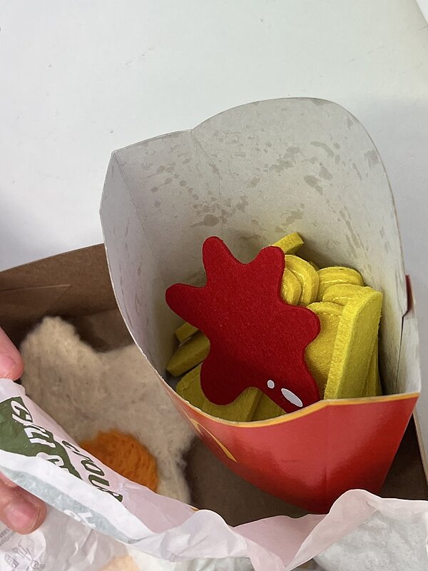 Selbstgemachte, unechte Pommes mit Ketchup in einem typischen Pappbehälter einer Fastfood Kette.