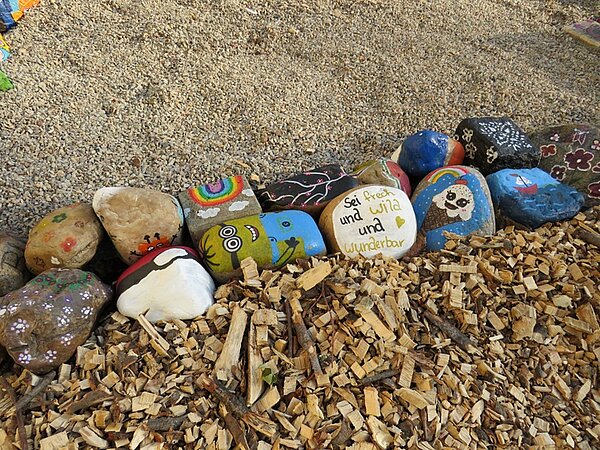 Kreativ und bunt bemalte Steine, die den Sinnespfad begrenzen. 