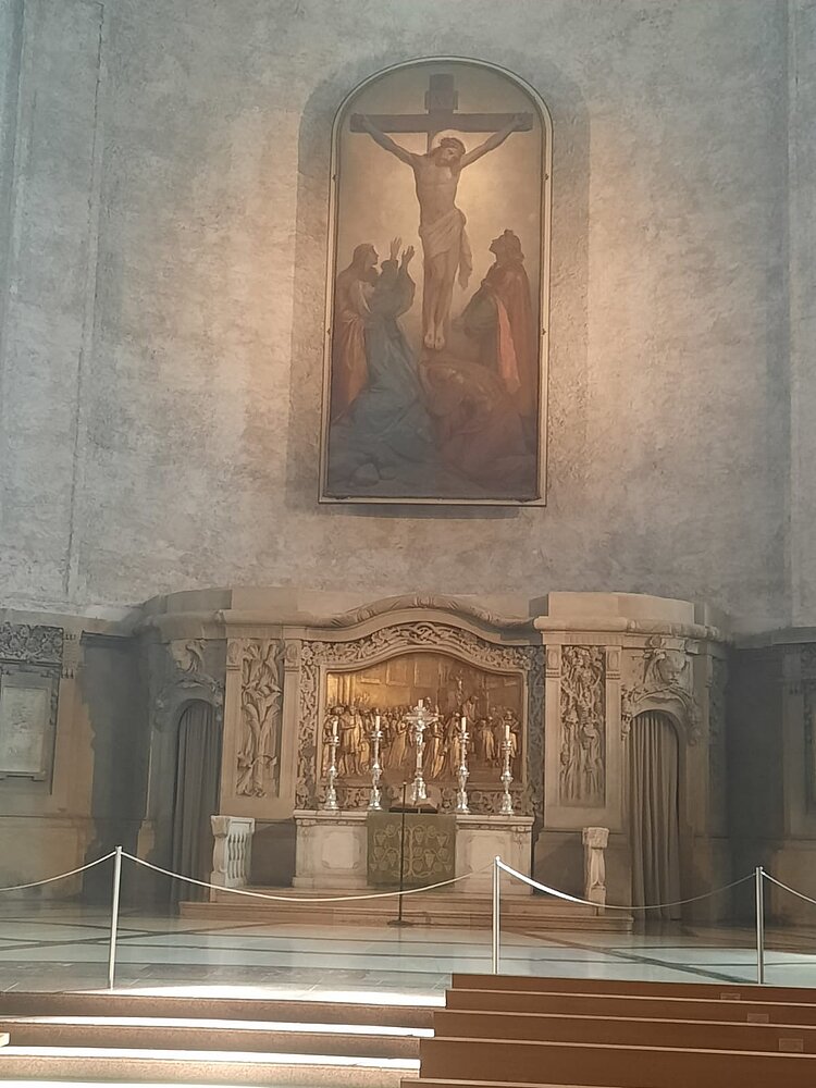 Ethikunterricht mal anders Kircheninnenraum mit Altar, geschmückt mit Reliefs und silbernen Kerzenständern. Darüber ein großes Gemälde der Kreuzigung Jesu, das von warmem Licht angestrahlt wird.