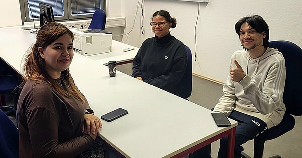 Erasmus-Speed-Dating Drei Auszubildende der Euro Akademie Hannover sitzen gemeinsam an einem weißen Tisch und posieren lächelnd für ein Foto.