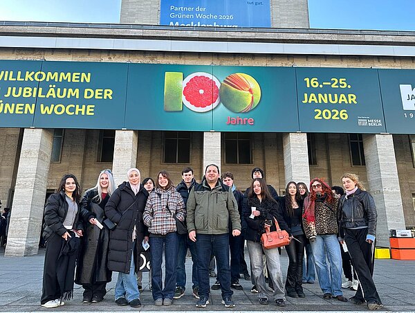 Schülergruppe vor dem Eingang einer Messehalle, darüber ein Banner mit den Worten "Jubiläum" und "100 Jahre"