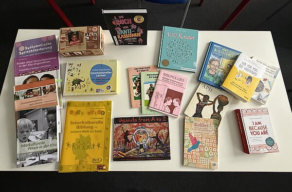 Foto von einem Tisch mit vielen bunten Büchern über interkulturelle Bildung