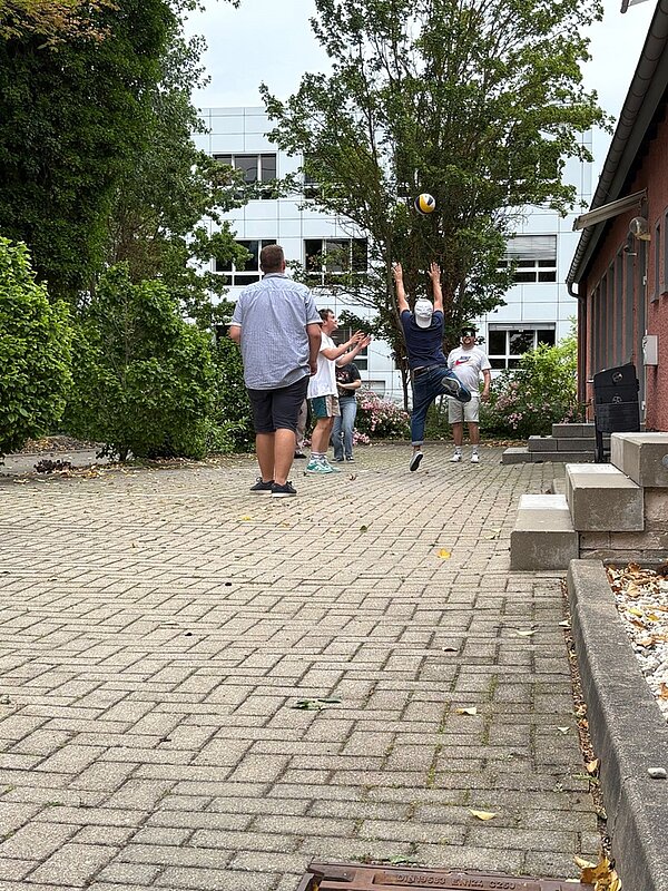 Sommerliches Abschlussfest an der Euro Akademie Jena Schülerinnen und Schüler spielen draußen Volleyball.