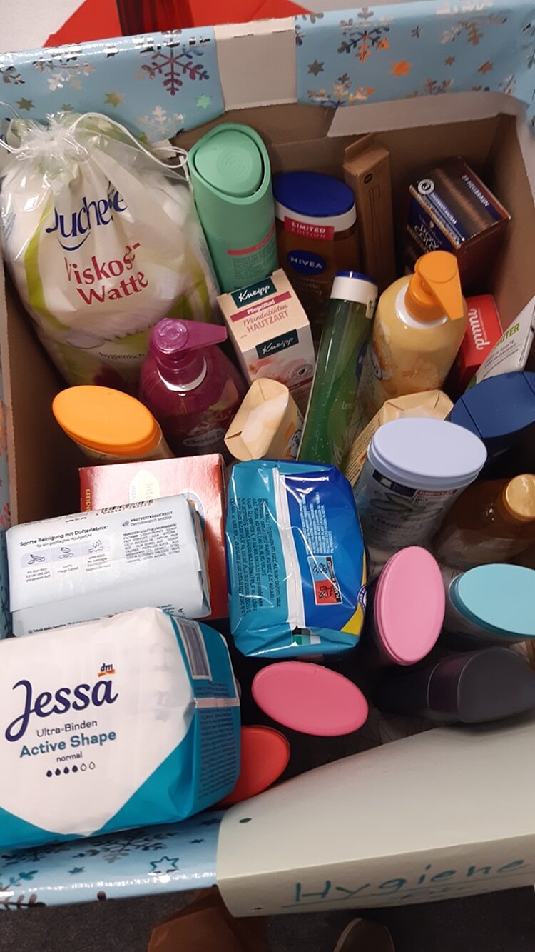 Soziales Projekt: Solidarität zeigen Karton mit gespendeten Hygieneartikeln wie Duschgel, Damenbinden, Shampoo, Zahnpasta und mehr.