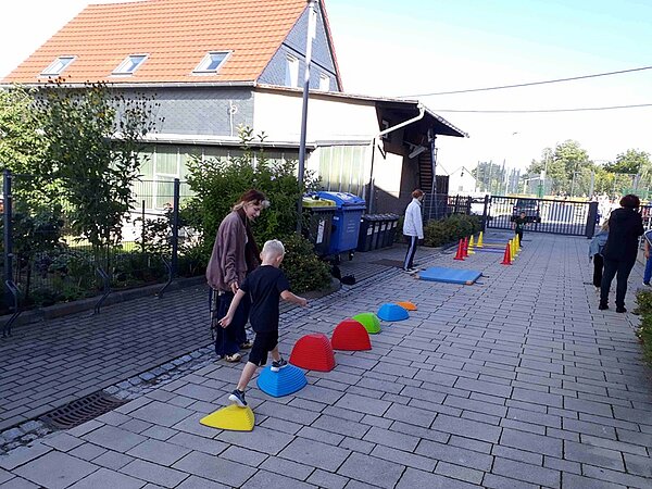 Kinder balancieren auf bunten Hügelkuppen.