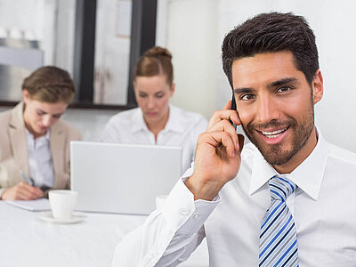 Drei Personen nehmen an einem Meeting teil. Die professionelle Interaktion steht im Vordergrund.