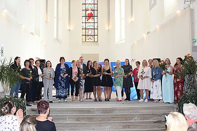 Gruppenfoto der Absolvent*innen der Euro Akademie Görlitz und Zittau auf der Treppe vor dem Altar.