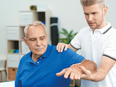Auf dem Bild ist ein Physiotherapeut, der einen älteren Patienten behandelt. Es zeigt einen Moment professioneller Gesundheitsfürsorge.
