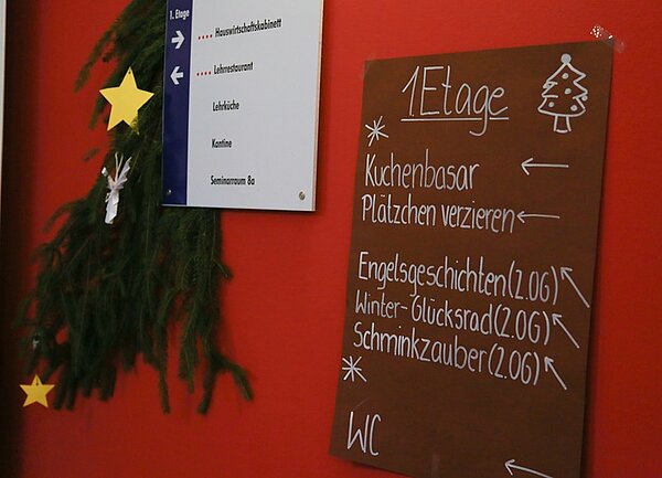 Ein Tannenbaumzweig hängt an der Wand, daneben eine Tafel, die die Aktivitäten anzeigt.