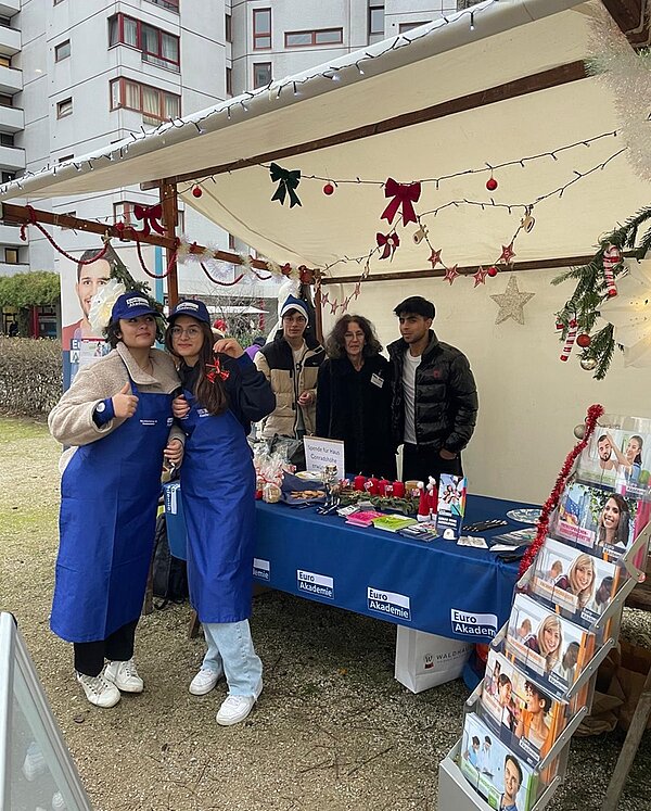 Schülerinnen und Schüler posieren schnell für ein Gruppenfoto und bauen noch ihren Wintermarkt-Stand auf.