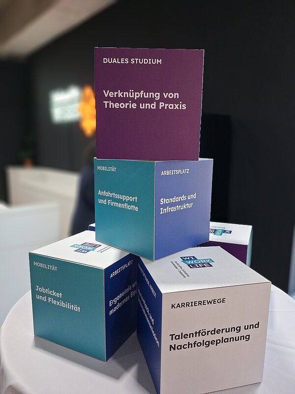 Auf einem Tisch stehen Informationswürfel mit Themen zu Ausbildung, Praktika und Arbeitsbedingungen.